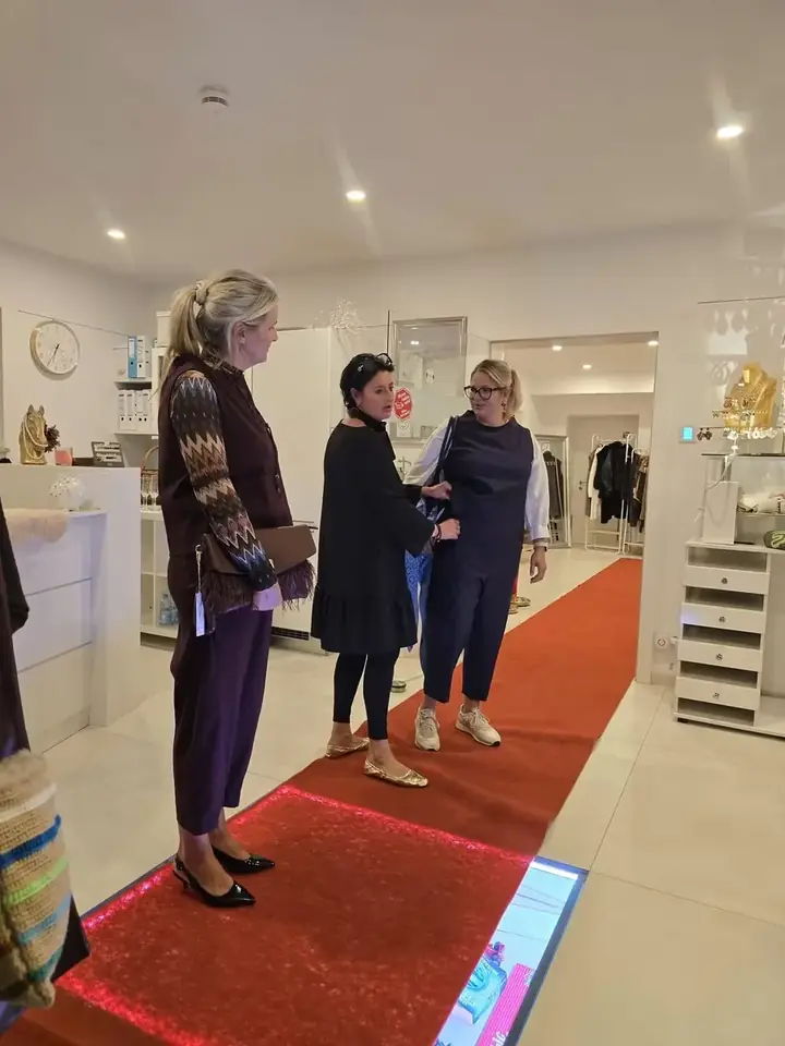 Herbstmodenschau 2026 im Mode-Atelier Völkl: drei Frauen zeigen Herbstlooks in Aubergine und Marine auf dem roten Laufsteg im Atelier in Haar bei München