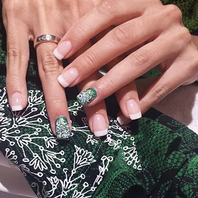 Nail-Art mit floralem Muster auf grünem Untergrund
